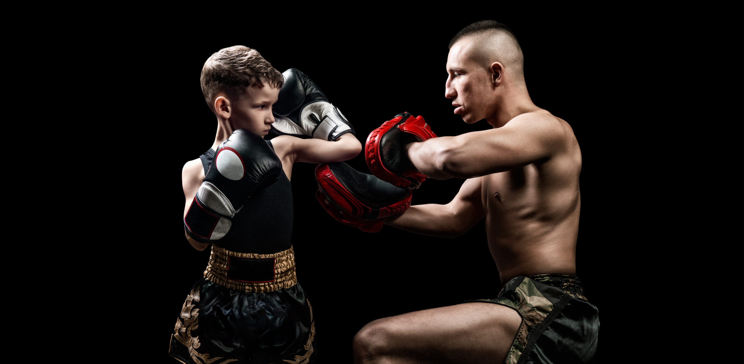 Thai boxing coach practicing punches with his student. Kickboxin teen mma classes